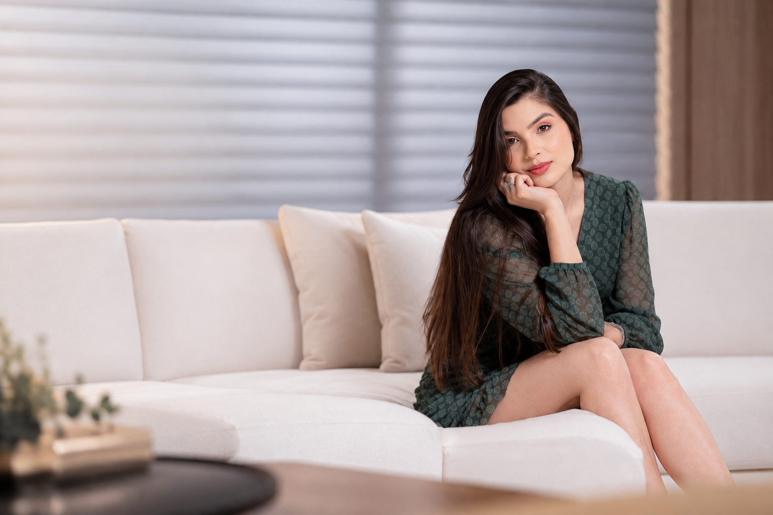 Gabriella Sauder sentada em um sofá claro, usando um vestido verde